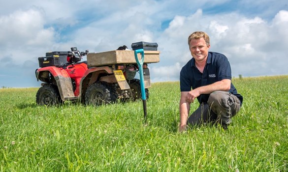 Beef & Lamb farmer David Cross knelt down in a field with a spade